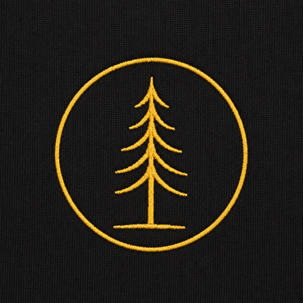 Close-up of the gold embroidered EVAREN tree emblem on black hoodie fabric