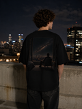 The Ordinary Sky Tee worn on a rooftop at night, showing the large city-window and night-sky back artwork.