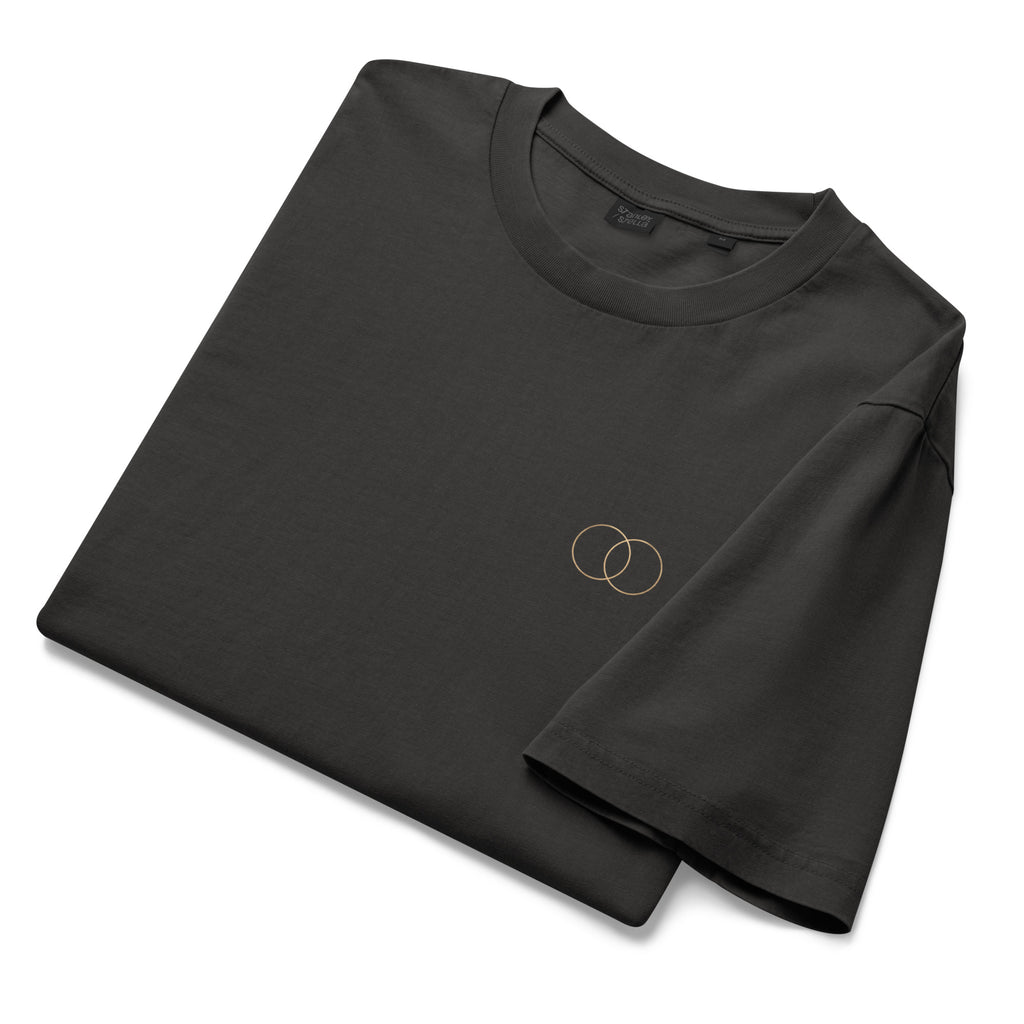 Folded EVAREN The Other Version Tee showing the garment-dyed Black Rock fabric and overlapping-circle chest detail.