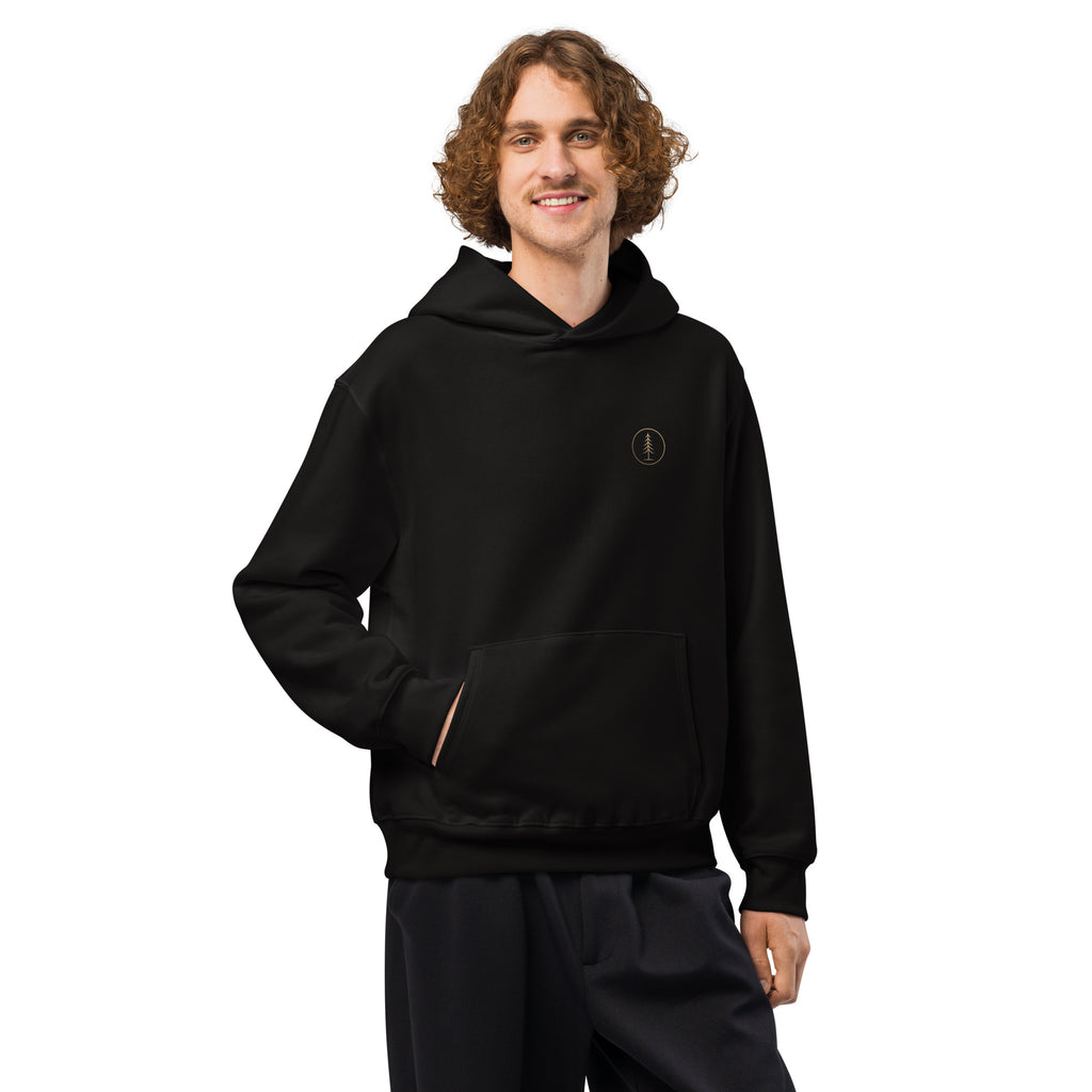Man wearing the black oversized EVAREN Headed There Hoodie from the front, showing the relaxed fit and small chest emblem.