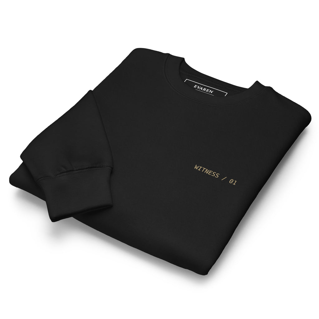 Folded black Witness Sweatshirt showing the subtle WITNESS / 01 chest mark and crewneck construction.